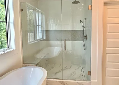 Image of shower area with frameless door panel and bench seat from Shower Door King.